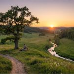 Sonnenuntergang im idyllischen Flusstal mit markanter Eiche